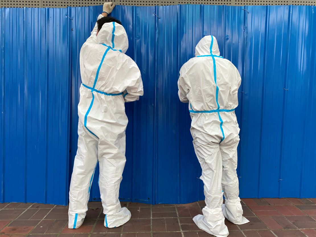 Workers in hazmat suits set up barriers outside a building in Shanghai on June 9 to prevent residents from leaving.