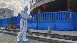 FILE - A worker in protectively overalls and carrying disinfecting equipment walks outside the Wuhan Central Hospital, China on  Feb. 6, 2021. Experts drafted by the World Health Organization to help investigate the origins of the coronavirus pandemic say further research is needed to determine how COVID-19 first began. They say they need a more detailed analysis of the possibility it was a laboratory accident. (AP Photo/Ng Han Guan, File)