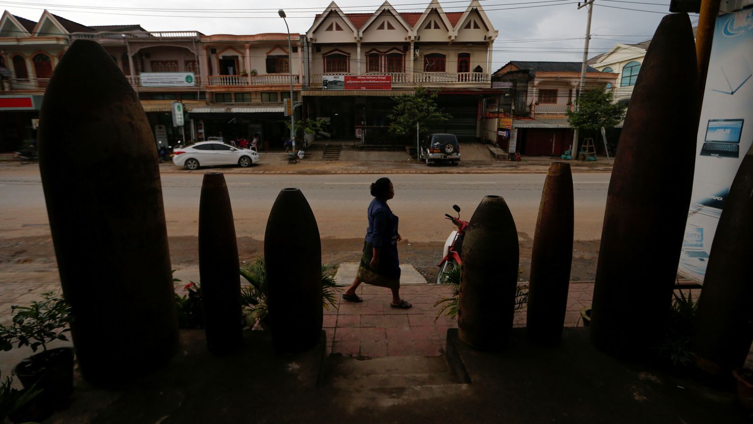 A woman walks past a restaurant littered with unexploded bombs dropped by US Air Force planes during the Vietnam War, in Xieng Khouang, Laos September 2, 2016.