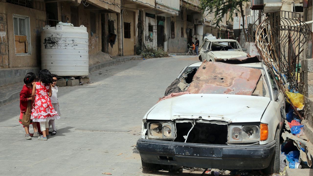 Children walk past a shrapnel-ridden vehicle in Yemen's rebel-besieged third city of Taez on June 9. In Yemen, millions have been forced from their homes in the brutal conflict pitting the Saudi-backed government against Iran-backed Houthi rebels, which has sparked widespread food shortages and ravaged the country's infrastructure.