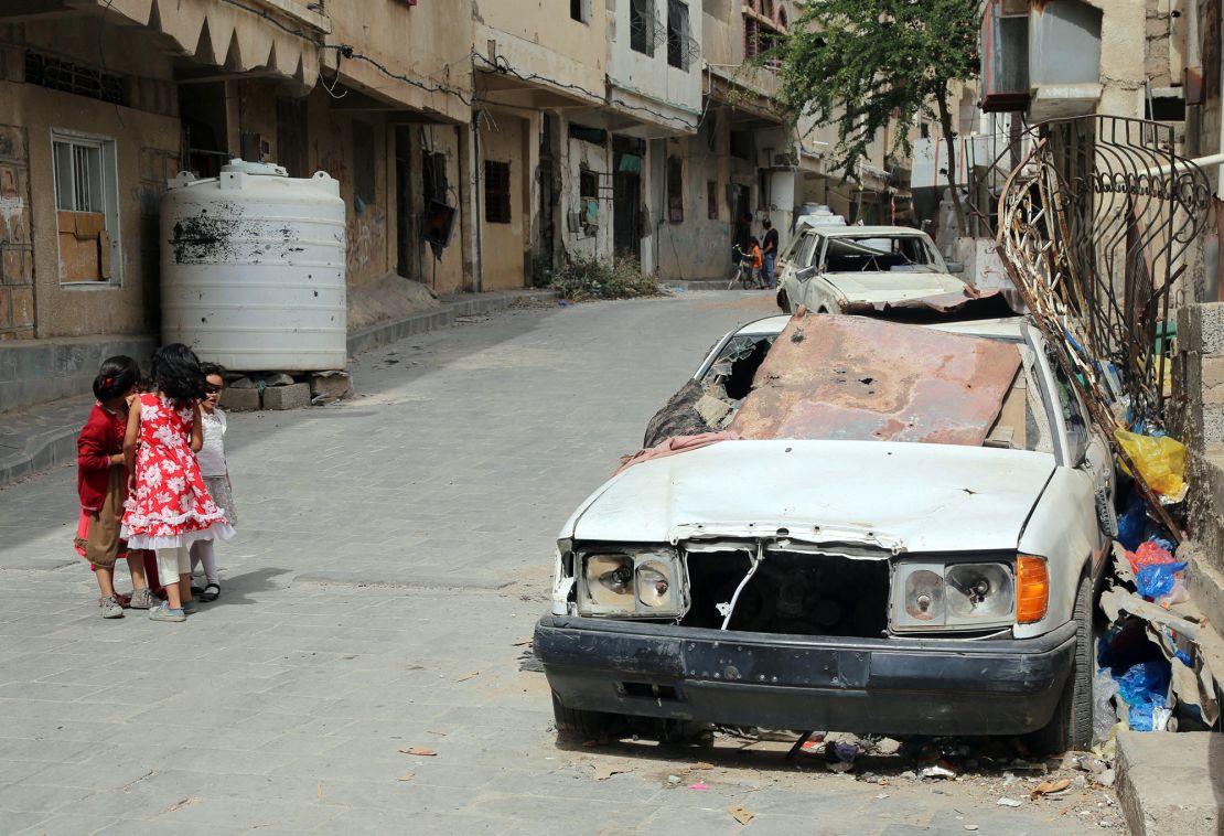 Children walk past a shrapnel-ridden vehicle in Yemen's rebel-besieged third city of Taez on June 9. In Yemen, millions have been forced from their homes in the brutal conflict pitting the Saudi-backed government against Iran-backed Houthi rebels, which has sparked widespread food shortages and ravaged the country's infrastructure.  