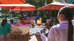 A worker serves a drink in the outdoor seating area of the Sant Ambroeus restaurant at the Royal Poinciana Plaza in Palm Beach, Florida, U.S., on Wednesday, Feb. 23, 2022. 