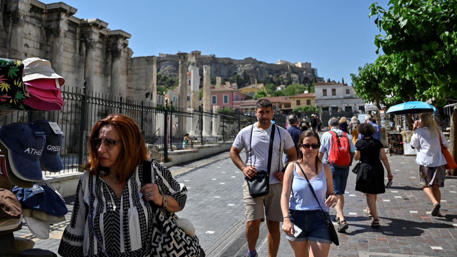 Tourists and locals  walk in a touristic area of Athens on June 1, 2022. - Greece dropped most mask mandates linked to Covid-19 restrictions starting June 1 to mid-September, a period coinciding with the height of its vital tourism season. (Photo by Louisa GOULIAMAKI / AFP) (Photo by LOUISA GOULIAMAKI/AFP via Getty Images)