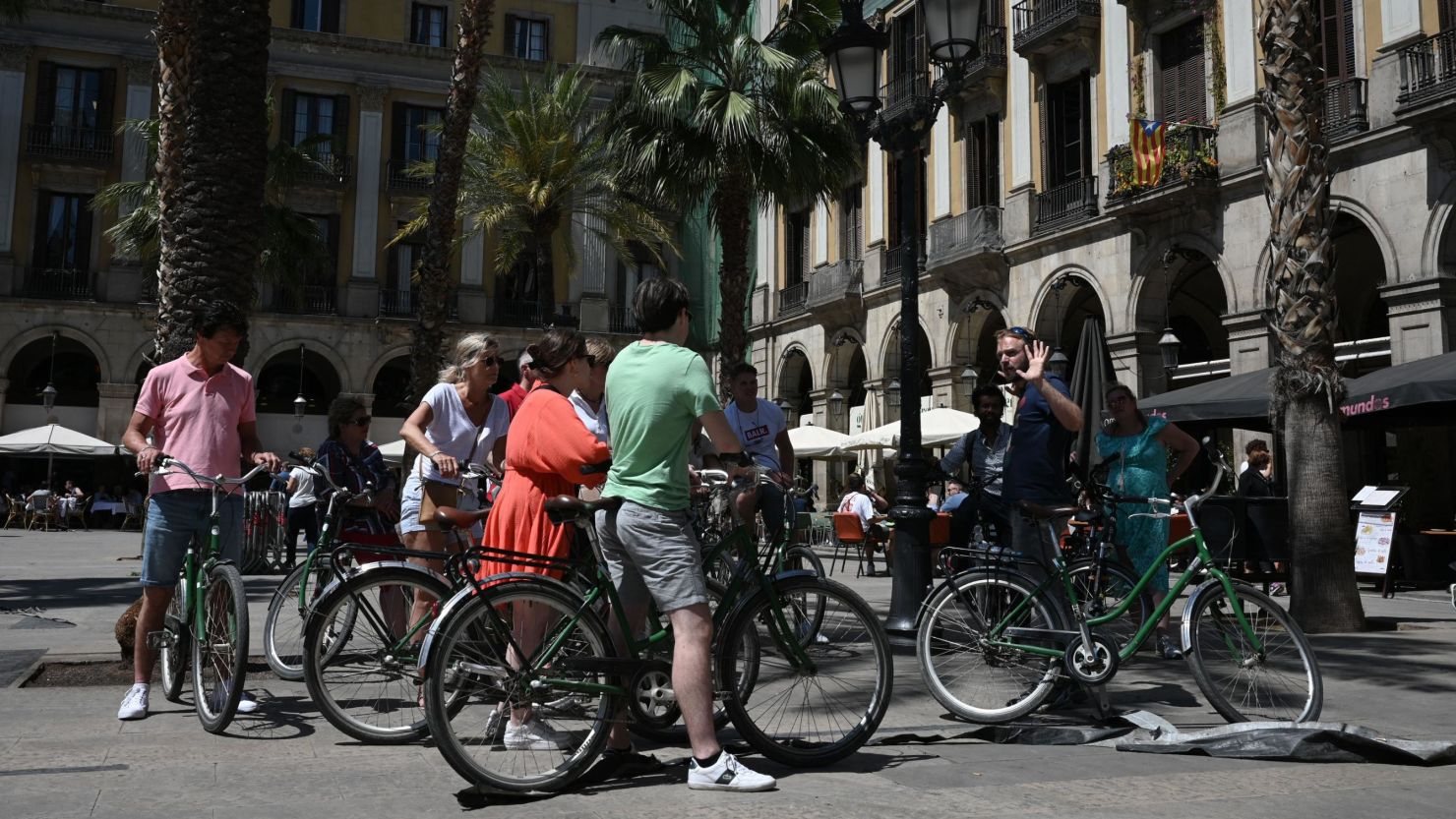 Tourists on bicycles listen to a tour guide at Plaza Real in Barcelona, on May 11, 2022.