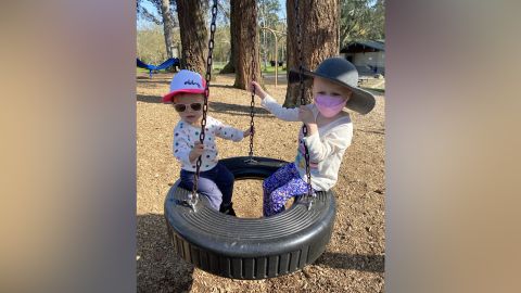 Olivia (right), 4, wears a mask while playing outside with her 20-month-old sister Abigail (left).