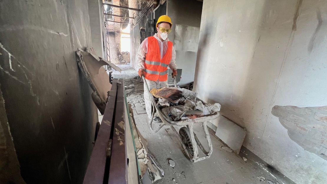 A volunteer clears debris from the damaged apartment block.