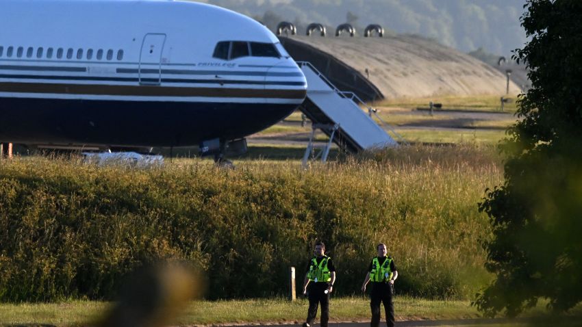 Two police officers walk in grounds near to where a Boeing 767 sits on the runway at the military base in Amesbury, Salisbury, on June 14, 2022, preparing to take a number of asylum-seekers to Rwanda. - The British government was to send a first plane carrying failed asylum seekers to Rwanda on Tuesday despite last-gasp legal bids and protests against the controversial policy. A chartered plane will land in Kigali on Tuesday, campaigners said, after UK judges rejected an appeal against the deportations. (Photo by JUSTIN TALLIS / AFP) (Photo by JUSTIN TALLIS/AFP via Getty Images)