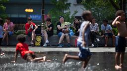 People sit in the shade as children play with water in downtown Chicago, the United States, on June 14, 2022. The Chicago metropolitan area is bracing for a heat wave, as the U.S. National Weather Service issued a heat advisory for the area on Monday. (Photo by Vincent D. Johnson/Xinhua via Getty Images)