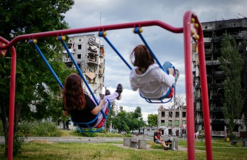 Young people swing in front of destroyed residential buildings in Borodyanka, Ukraine, on June 15.