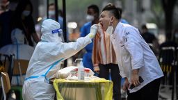 TOPSHOT - A health worker takes a swab sample from a man to be tested for the Covid-19 coronavirus at a makeshift testing site outside a shopping mall in Beijing on June 15, 2022. (Photo by Jade GAO / AFP) (Photo by JADE GAO/AFP via Getty Images)