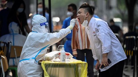 A health worker takes a swab sample from a man at a makeshift testing site outside a shopping mall in Beijing on June 15, 2022.