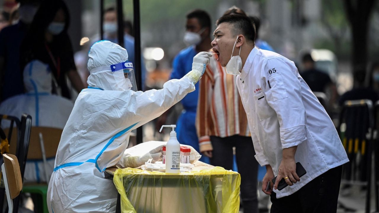A health worker takes a swab sample from a man at a makeshift testing site outside a shopping mall in Beijing on June 15, 2022.
