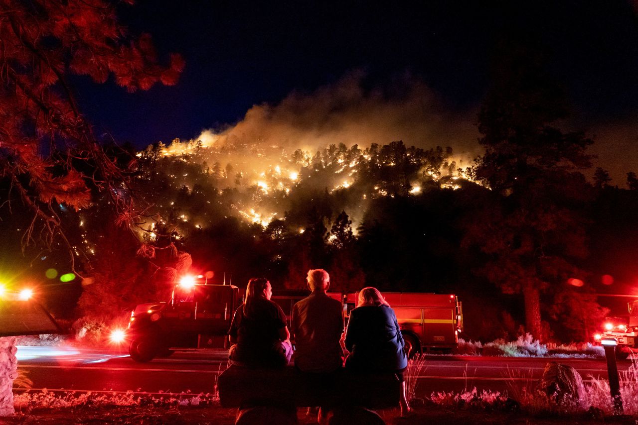 People watch part of a wildfire burn through a forest near their homes in Wrightwood, California, on Saturday, June 11. The Sheep Fire began on Saturday evening. Its cause remains under investigation.