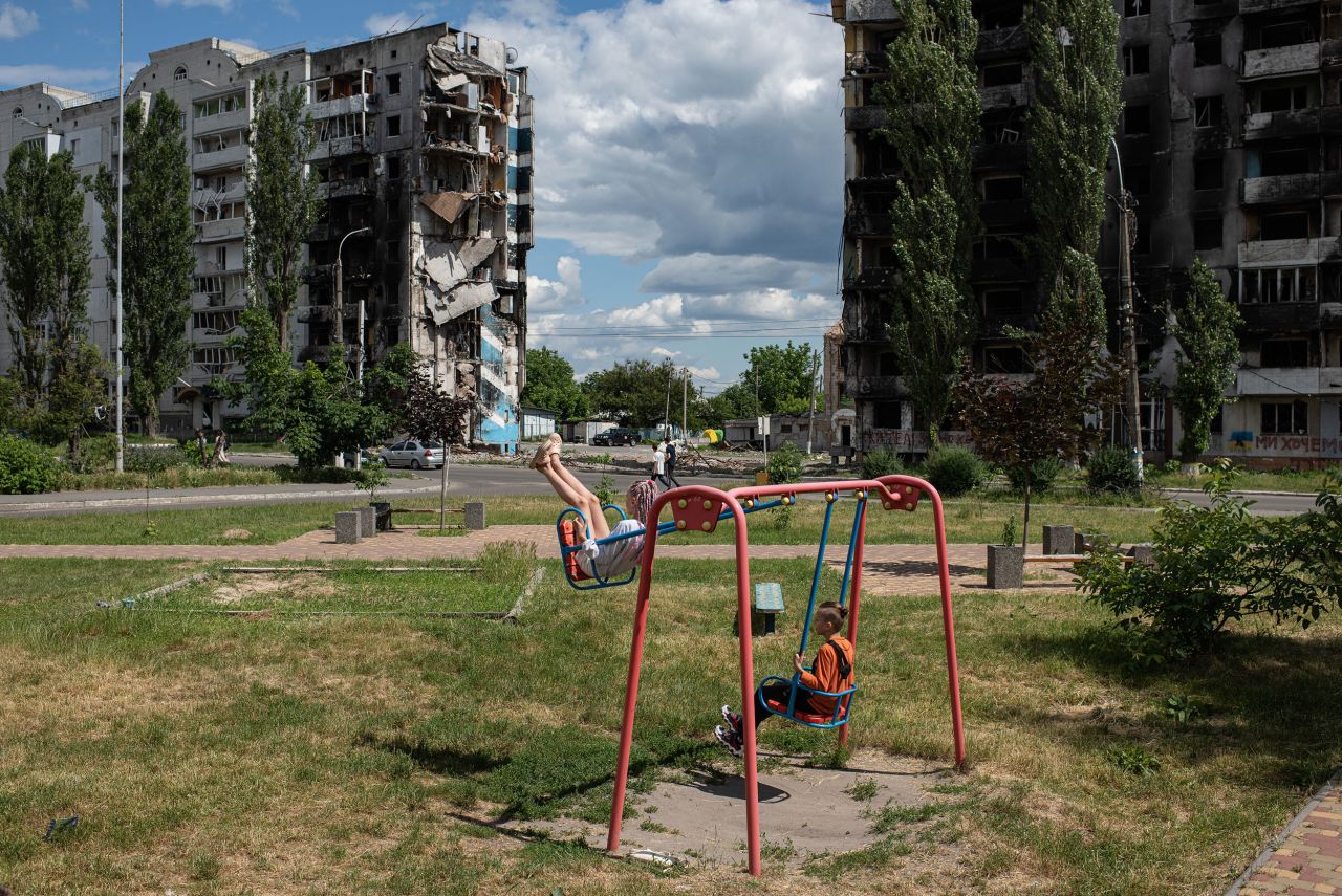 A girl and a boy play on a swing set next to a shelled apartment building in Borodianka, Ukraine, on Wednesday, June 15. <a href="http://www.cnn.com/2022/02/14/world/gallery/ukraine-russia-crisis/index.html" target="_blank">Russia invaded Ukraine in February,</a> and fierce fighting continues in the country.