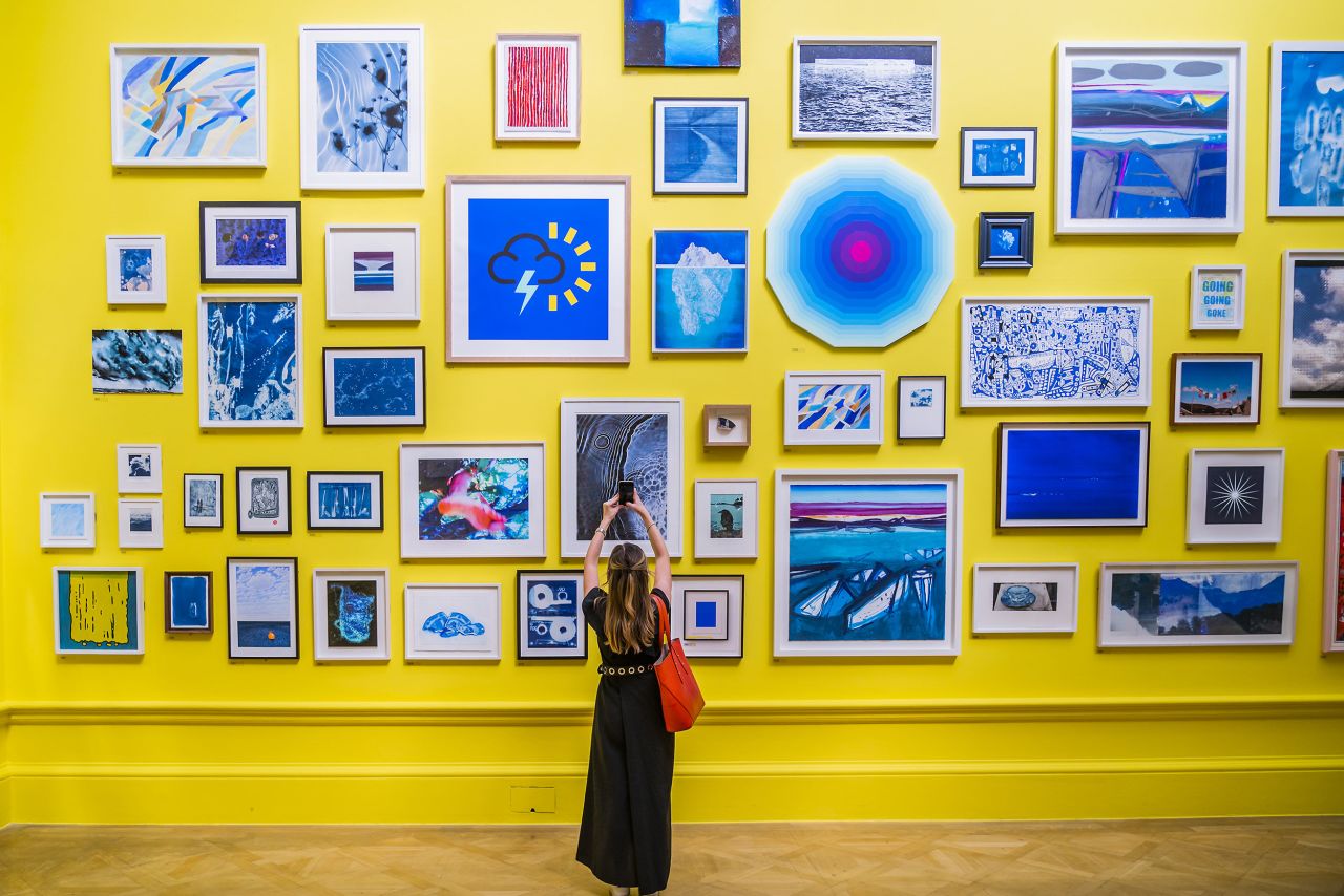 A woman uses her phone Tuesday, June 14, inside the Royal Academy of Arts in London. The works in this room explore the theme of climate.