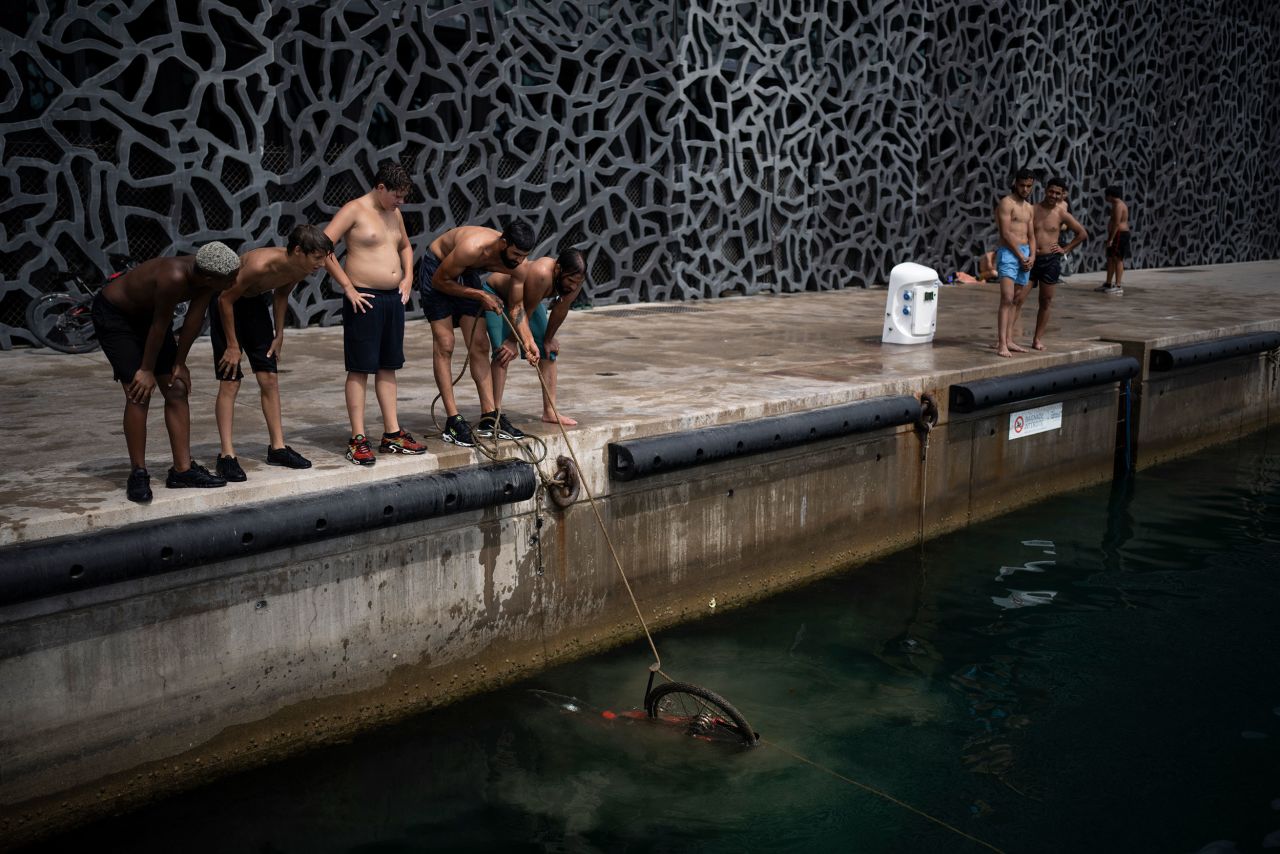 Swimmers pull a bicycle out of the port of Marseille, France, on Wednesday, June 15.