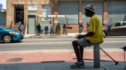 A man sits in the shade a people wait at a bus stop in the Bronx borough of New York, U.S., on Saturday, July 20, 2019. Consolidated Edison Inc. is forecasting record power demand for New York this weekend as a heat wave blankets the city. Photographer: David 'Dee' Delgado/Bloomberg via Getty Images