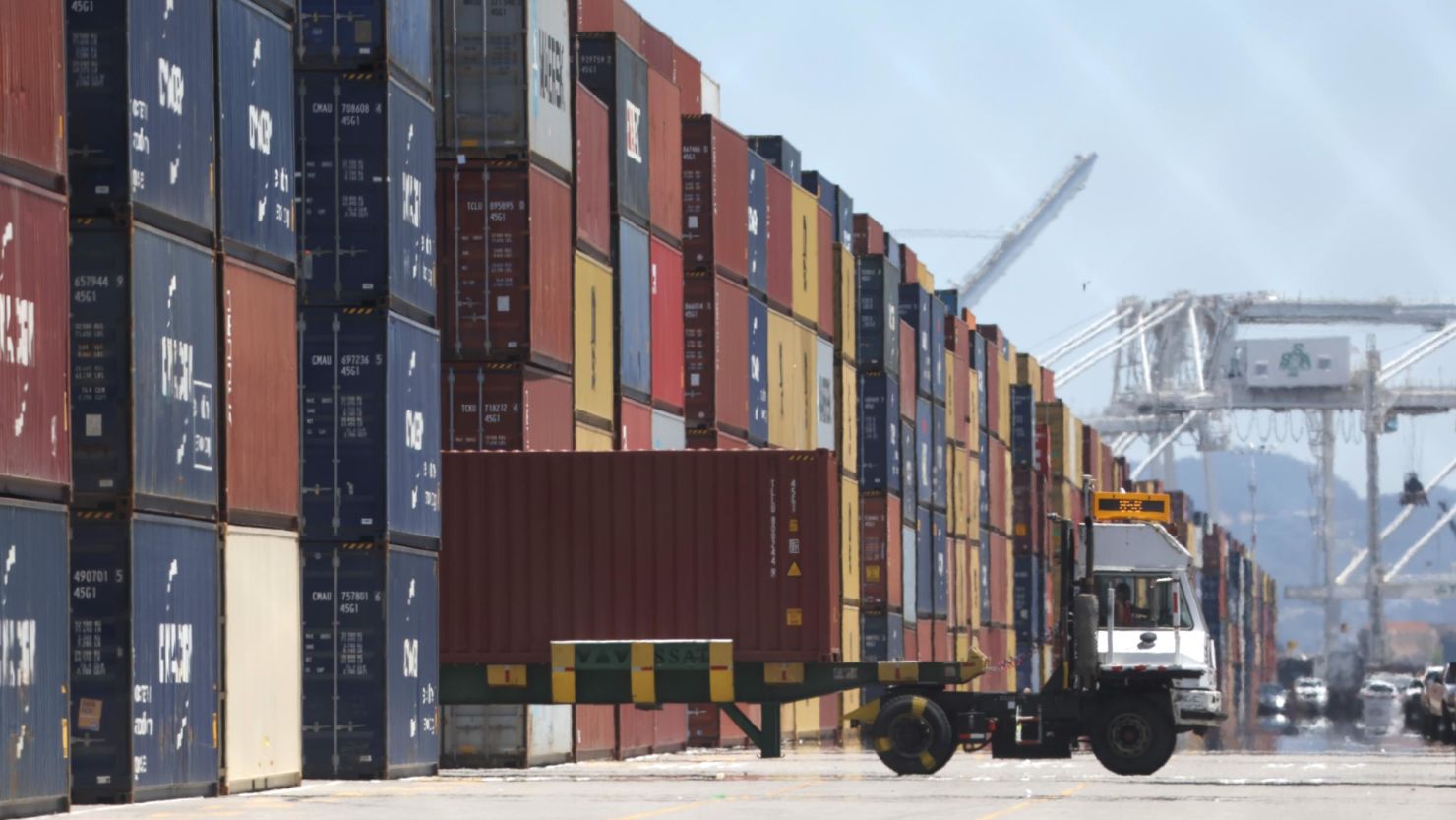 A truck drives by stacks of shipping containers at the Port of Oakland in California on May 20, 2022.