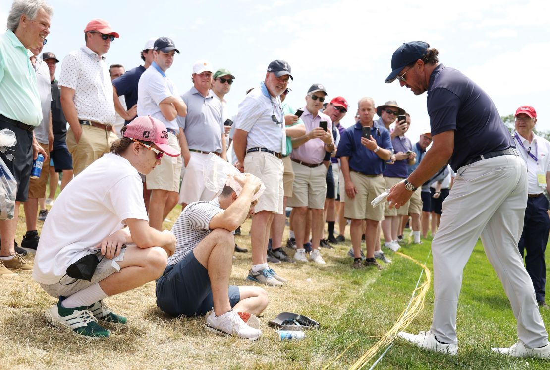 Mickelson attending to a fan struck by his ball at the third hole.
