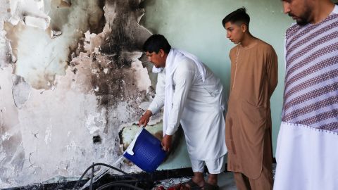 A man pours water over smoldering ashes inside a house damaged when an explosives-laden vehicle detonated amid an attack on a Sikh temple in Kabul. 