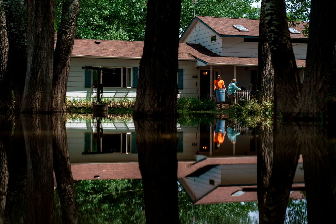 Water fills the front yard as Cody DeRudder, left, and family friend, Melody Murter, clean out DeRudder's family home after it was damaged by severe flooding in Fromberg on Friday.