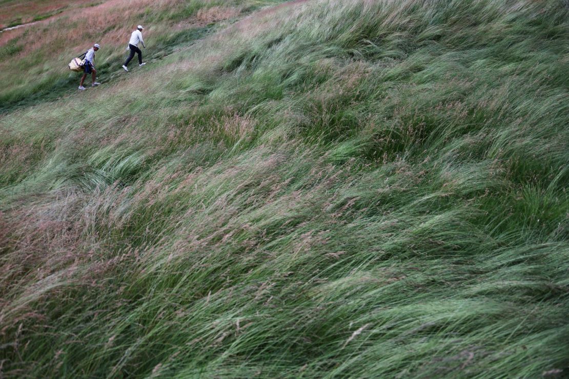 Scheffler and caddie Ted Scott brave the wind.