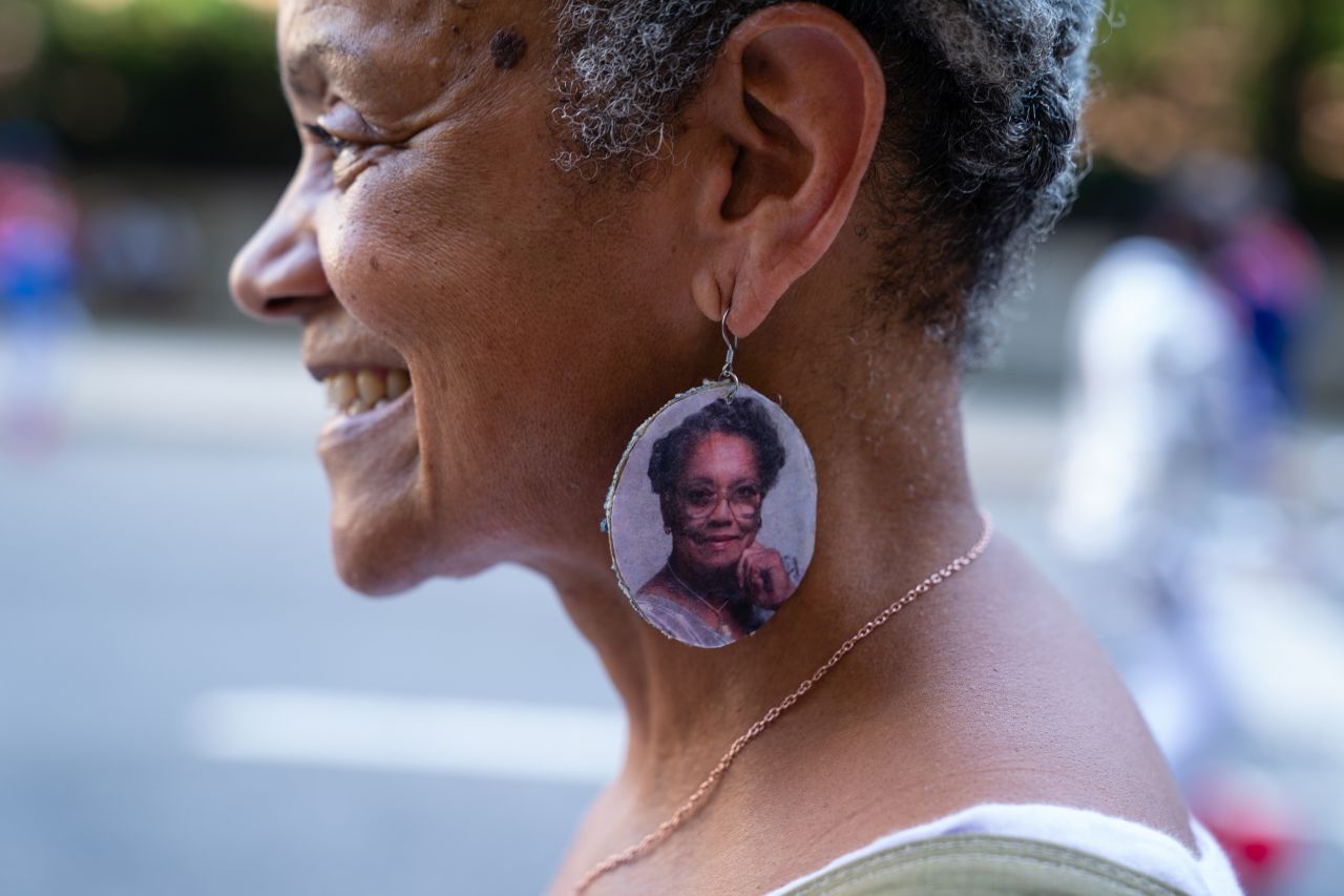 Bridget New wears earrings with an image of her grandmother, Cecile Desvigne New, while watching the Juneteenth Atlanta Black History parade on Saturday.