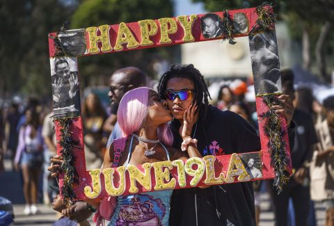 Daisa Chantel kisses Anthony Beltran as they take a picture to celebrate Juneteenth at Leimert Park in Los Angeles on Saturday.