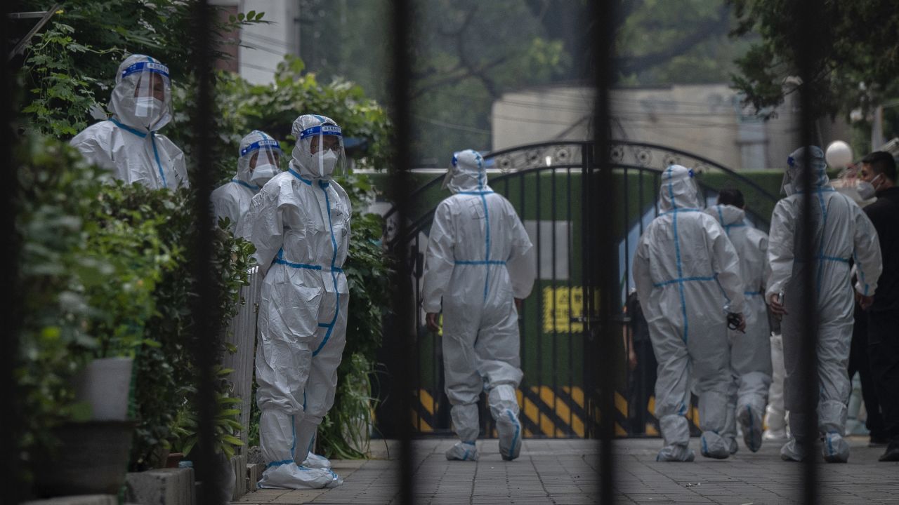 BEIJING, CHINA -JUNE 16: Health workers and security wearing protective clothing work inside a compound under lockdown after new COVID-19 cases were found in the area on June 16, 2022 in Beijing, China. China's capital is working to control a fresh COVID-19 cluster after dozens of people linked to a local nightclub tested positive for the virus. After easing restrictions earlier in the week, local authorities have initiated local mass testing and targeted lockdowns in addition to mandated proof of a negative PCR test within 72 hours to enter most public spaces and entertainment establishments and bars in some districts have been ordered to close in an effort to maintain the country's zero COVID strategy.  (Photo by Kevin Frayer/Getty Images)