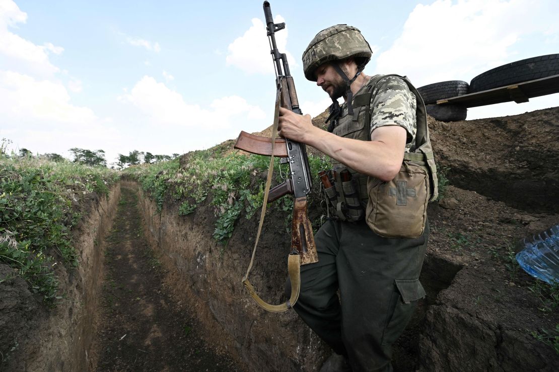 A Ukrainian serviceman walks in a trench on a position held by the Ukrainian army between southern cities of Mykolaiv and Kherson on June 12, 2022, amid the Russian invasion of Ukraine. 