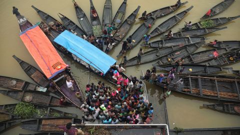 La gente si riunisce lunedì per raccogliere aiuti alimentari in una zona allagata a Companiganj, in Bangladesh. 
