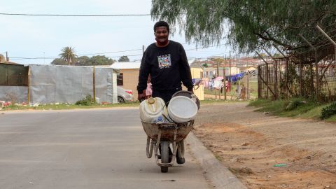 Morris Malambile says pushing a wheelbarrow filled with water containers every day is "tiring."