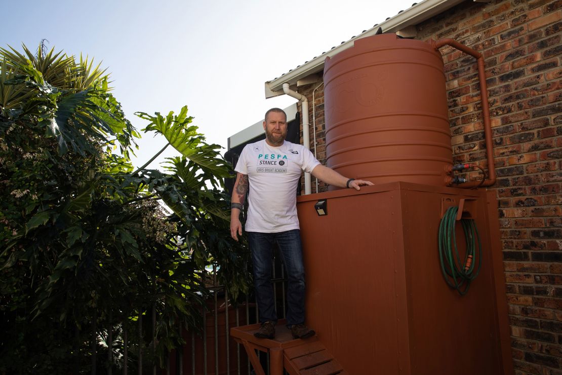 Rhett Saayman standing next to one of his several water tanks at his home in Kamma Heights.