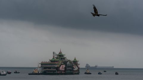 A bird flies above the Chinese imperial-style Jumbo Floating Restaurant as it is towed out of a typhoon shelter in Hong Kong on June 14, 2022.