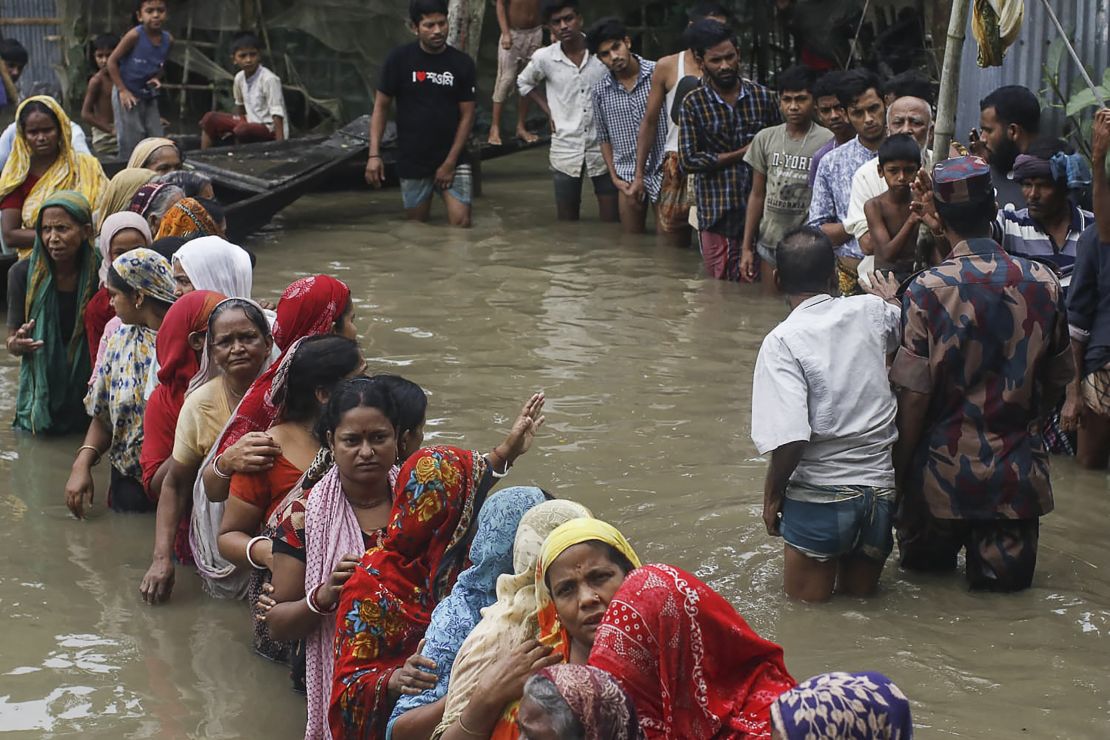 Flood affected people queue in knee-deep flood waters to collect food relief following heavy monsoon rainfalls in Sunamganj district, Bangladesh on June 21, 2022.