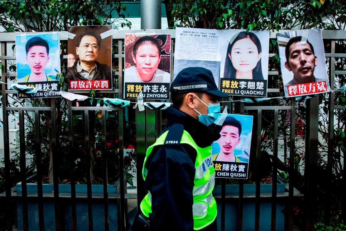 A police officer walks past placards calling for the release of detained Chinese rights activists taped on the fence of the Chinese liaison office in Hong Kong on February 19, 2020.