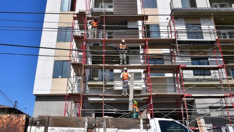 Construction workers pass planks of wood during the construction of new apartments in Monterey Park, California.