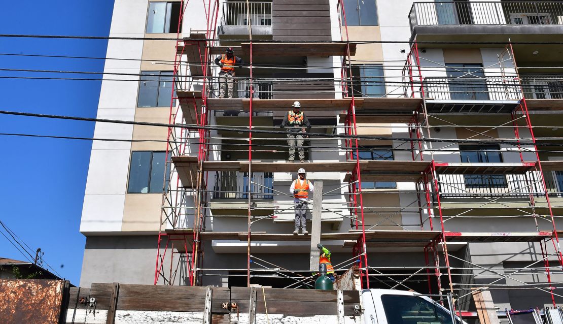 Construction workers pass planks of wood during the construction of new apartments in Monterey Park, California.