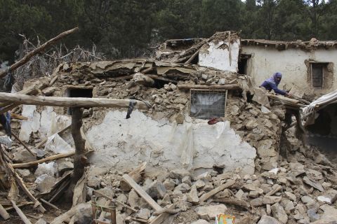 A villager collects his belongings from under the rubble of his home that was destroyed in the earthquake.
