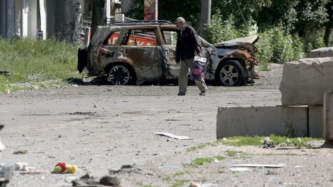 A man walks past the wreckage of a car in Lysychansk on June 21, 2022, as Ukraine says Russian shelling has caused 
