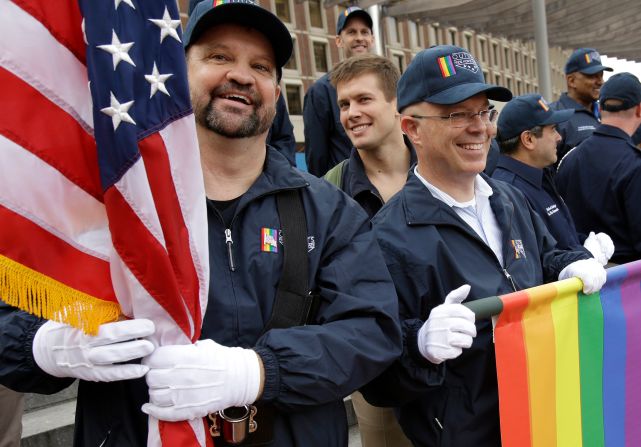 Retired U.S. Air Force Master Sgt. Eric Bullen, of Westborough, Mass., left, holds an American flag as U.S. Army veteran Ian Ryan, of Dennis, Mass., front right, rolls up an OutVets banner after marching with a group representing LGBT military veterans in a 2014 Veterans Day parade in Boston. It was the first time a group representing LGBT military veterans marched in the parade.