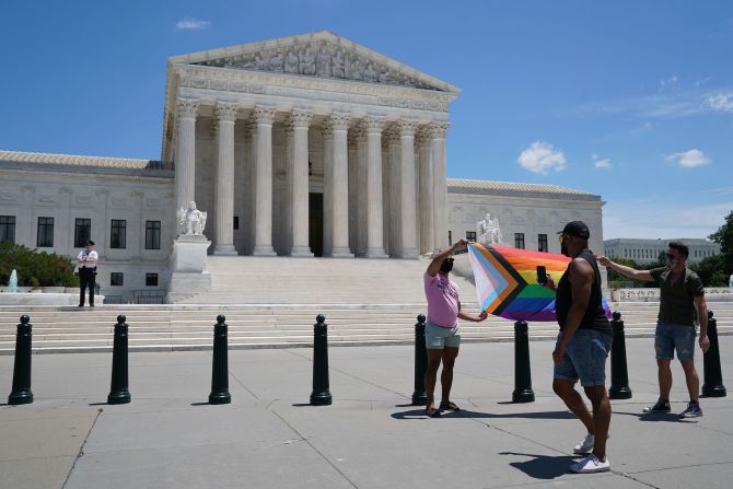 People display a flag featuring rainbow colors, in front of the Supreme Court in Washington, on Monday, June 15, 2020 when a landmark civil rights law was deemed as protecting gay and transgender workers from workplace discrimination. 