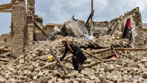 An Afghan man searches for his belongings among the ruins of an earthquake-damaged house. 