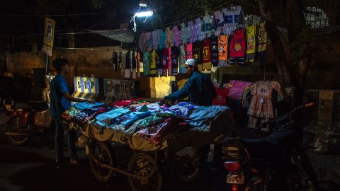 A vendor sells clothing under an emergency light attached to a motorcycle during a load-shedding power outage in Karachi, Pakistan, on June 8.