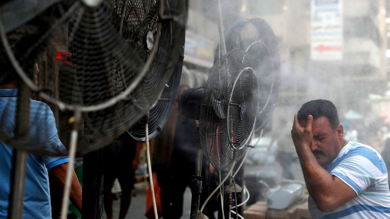 A man stands by fans spraying air mixed with water vapour deployed by donors to cool down pedestrians along a street in Iraq's capital Baghdad on June 30, 2021 amidst a severe heat wave. (Photo by AHMAD AL-RUBAYE / AFP) (Photo by AHMAD AL-RUBAYE/AFP via Getty Images)