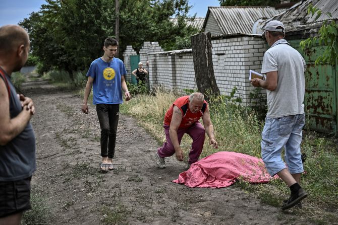 A man approaches the body of his son, who was reportedly killed by a cluster rocket in the city of Lysychansk, Ukraine, on Saturday, June 18.