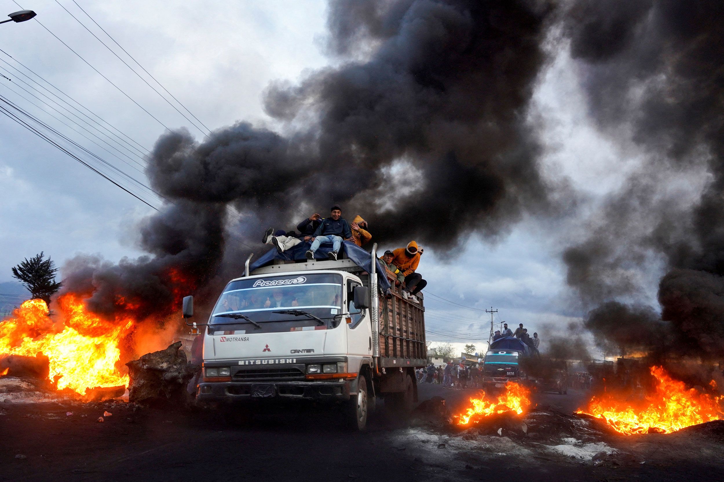 Indigenous demonstrators driving past burning road blockades in Machachi, Ecuador.