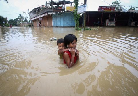 A girl carries her brother as she wades through a flooded road on the outskirts of Agartala, India on Saturday, June 18. Northeastern India and northern Bangladesh have been particularly badly hit by <a href=