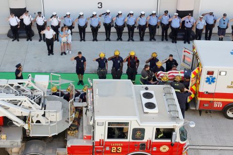 Firefighters and police officers salute as the body of Philadelphia firefighter Lt. Sean Williamson is unloaded from an ambulance in Philadelphia on Saturday, June 18. <a href=