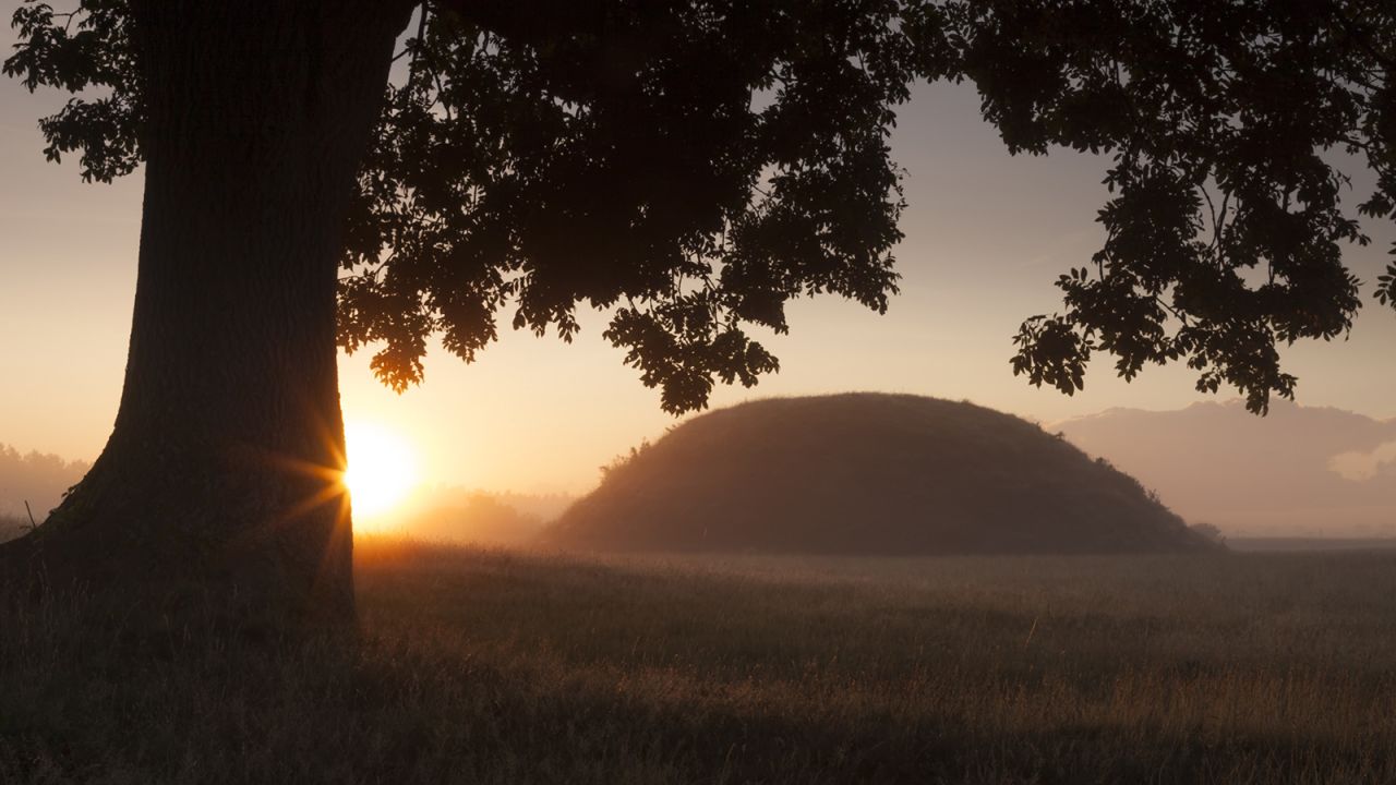 The sun sets over the famous burial mounds, shrouded by mist, at Sutton Hoo. 